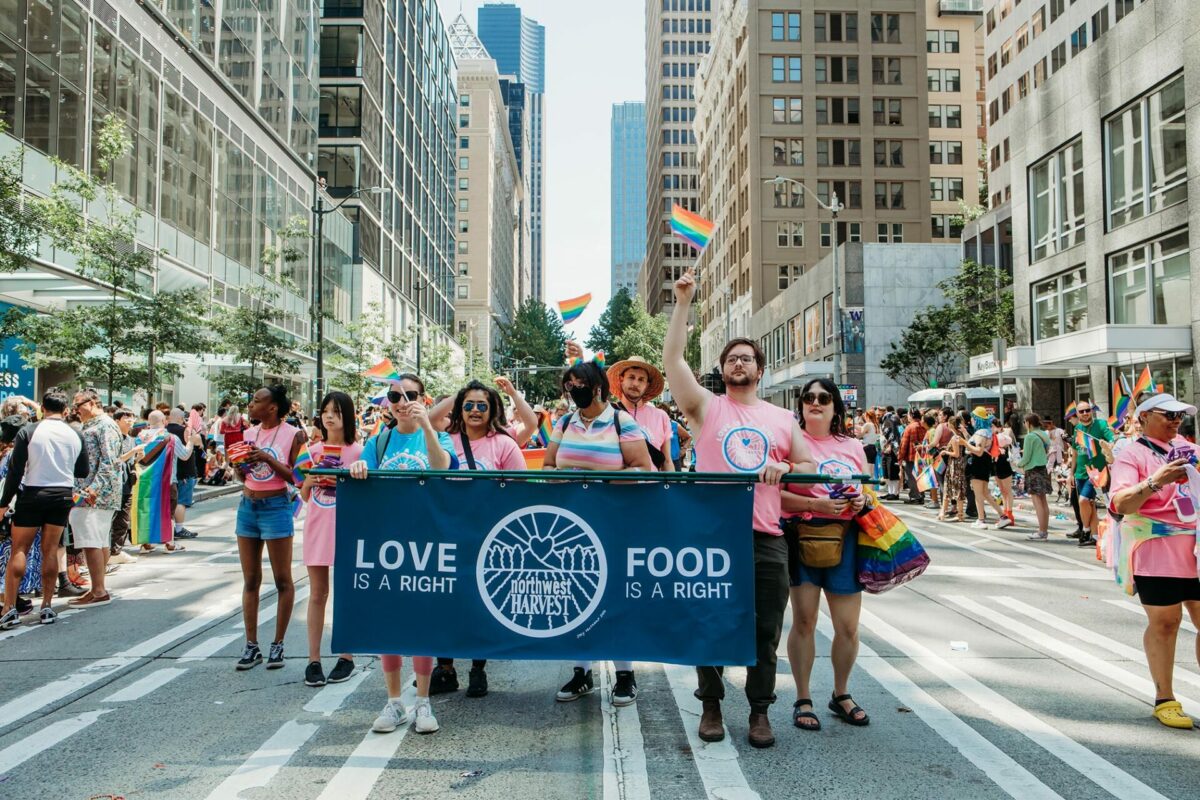 Northwest Harvest staff and volunteers march in the 2023 Seattle Pride Parade - group carries banner with 'love is a right-food is a right' message