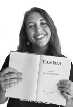 black and white photo of NWH volunteer, Brianna, who is holding up a book with the title, "Yakima"