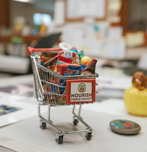 miniature shopping cart filled with mini grocery items and Nourish Pierce County logo on front