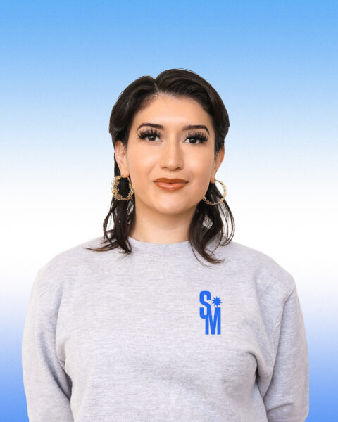 Santa Mercita subtly smiling in a great long sleeve and large gold hoop earrings.